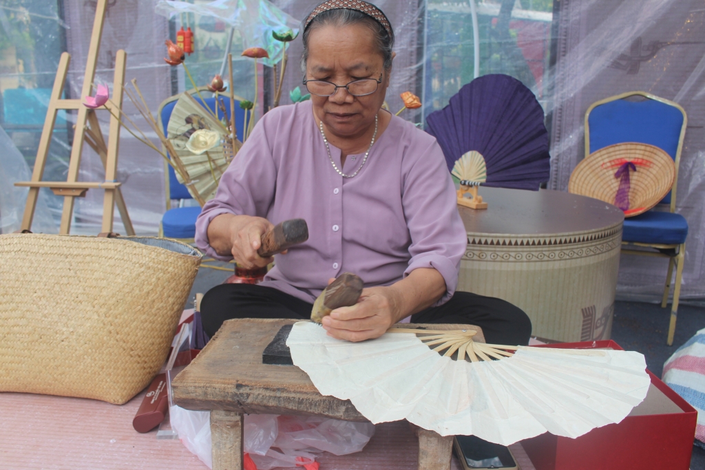 Bà Mai Thị Choi trình diễn kim châm trên quạt sừng giấy dó làng Vác tại Festival Thu Hà Nội năm 2024. Ảnh: Mộc Miên