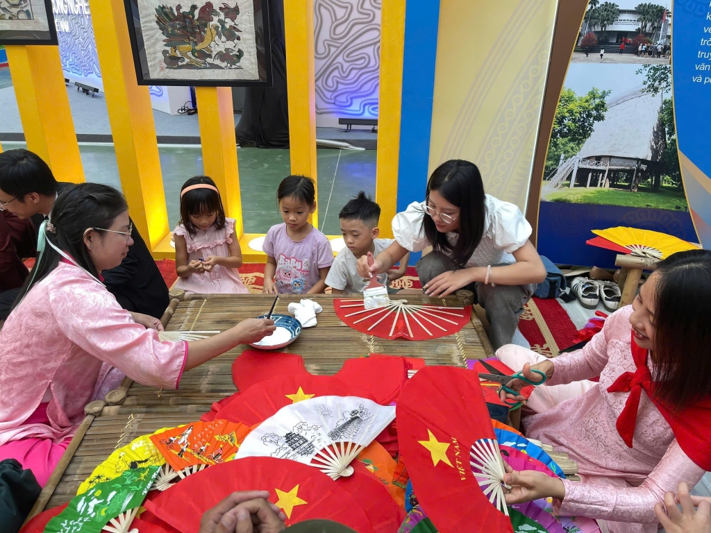 Các bạn nhỏ được hướng dẫn trang trí quạt mang hình ảnh lá cờ Việt Nam. Ảnh: Thu Trang
